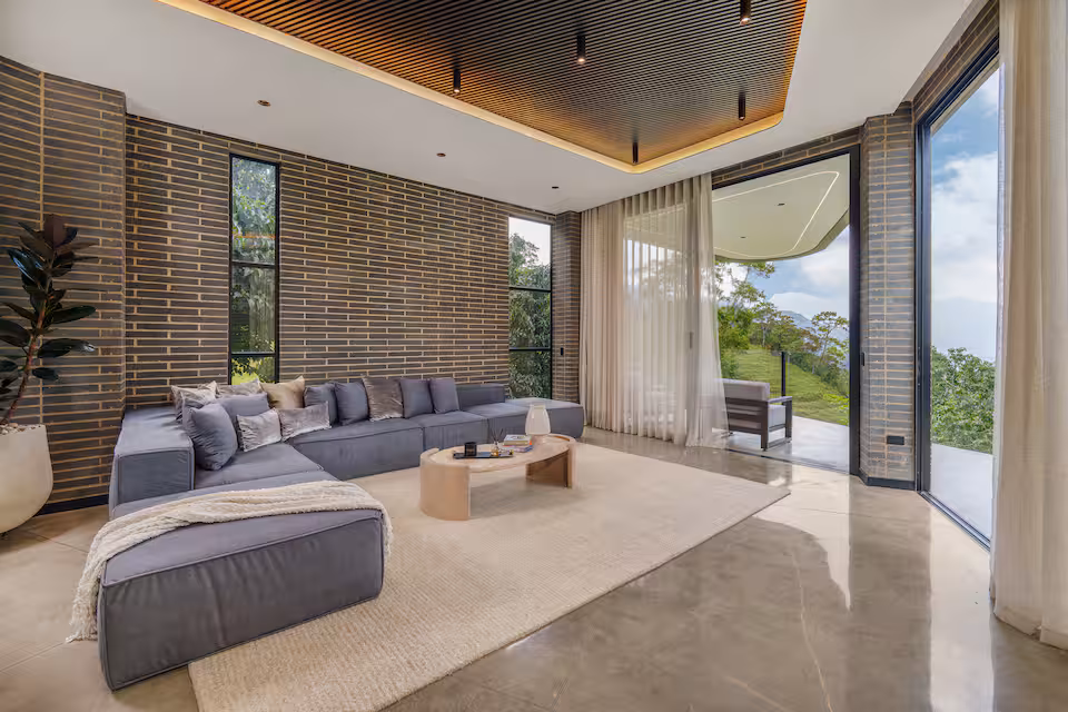 Villa lounge with floor-to-ceiling glass and hillside views